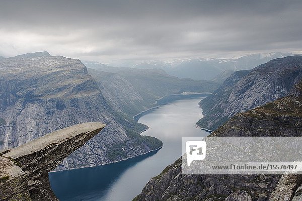 View of Trolltunga cliff and lake between mountains picturesque landscape beauty in nature paradise on Earth sunny day Odda Norway. cloudy day.