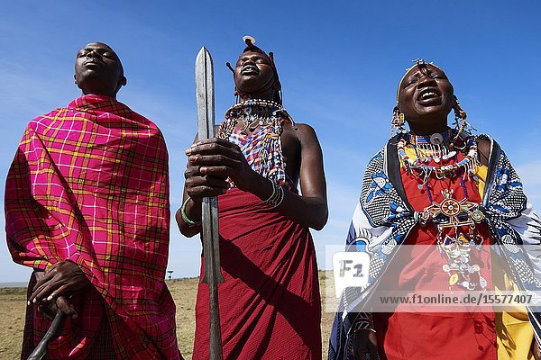 Group of Massai men and women singing and dancing Masai Mara National Reserve Kenya.