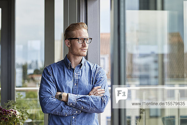 Young man standing at balcony door thinking