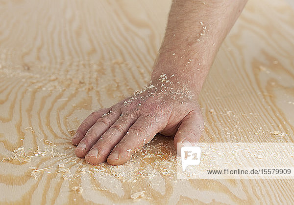 Human hand on wooden board with sawdust