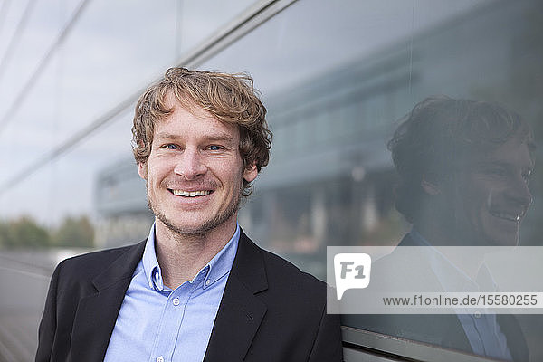Portrait of smiling businessman in front of glass facade