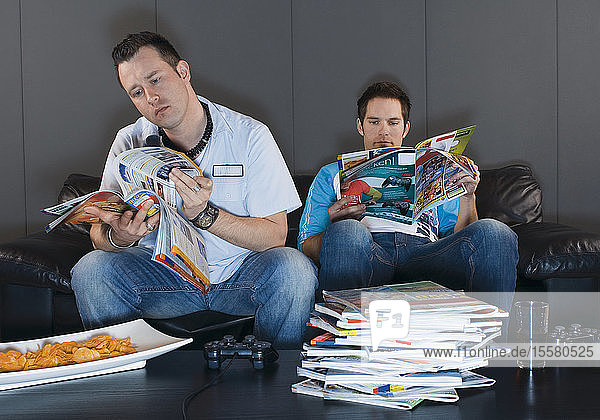 Männer  die auf der Couch sitzen und Zeitschriften lesen