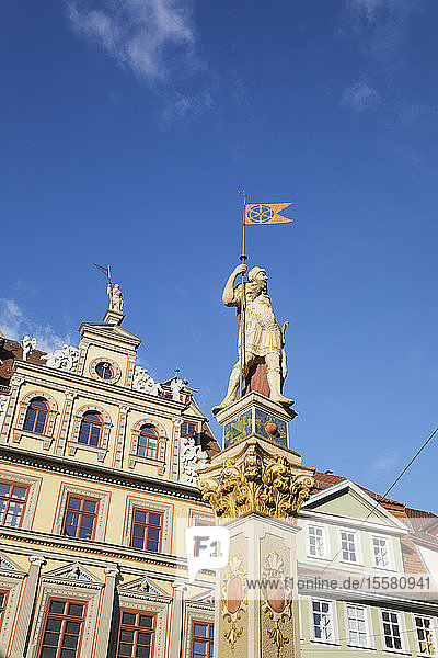 Niedrigwinkelansicht der Rolandstatue und des Renaissance-Gebäudes vor blauem Himmel in Erfurt  Deutschland