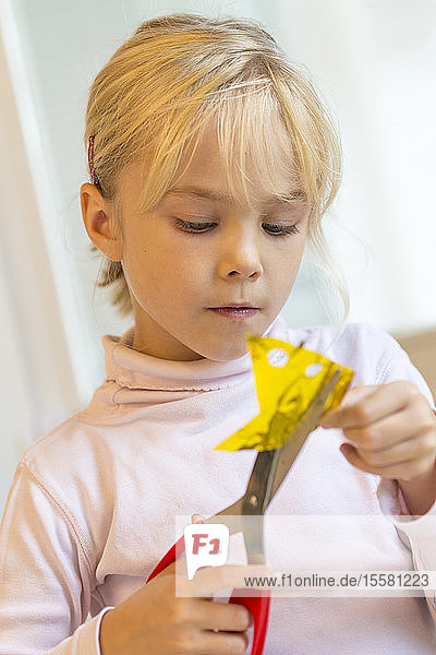 Kleines Mädchen bastelt mit Schere und Papier