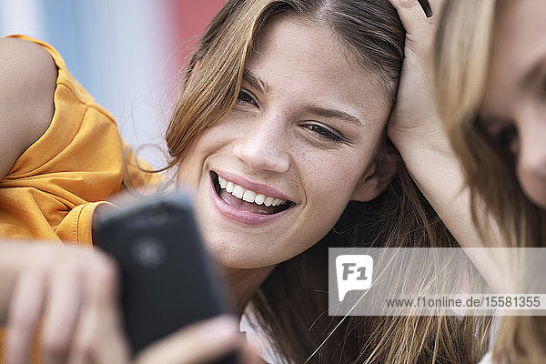 Deutschland  Köln  Junge Frau mit Handy  lächelnd