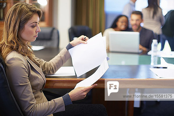 Businesswoman reading document in boardroom