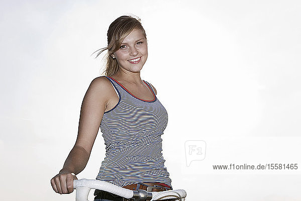 Germany  Cologne  Young woman with bicycle  smiling  portrait