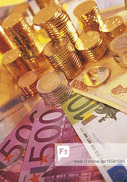 Nahaufnahme von Euro-Banknoten und Münzstapel