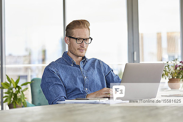 Young man sitting at table using laptop