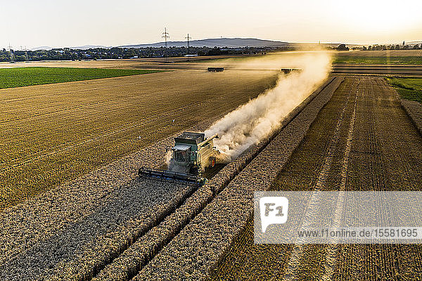 Aerial view of combine harvester on agricultural field against clear sky during sunset
