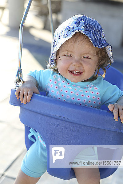 Porträt eines lächelnden Mädchens auf blauer Babyschaukel