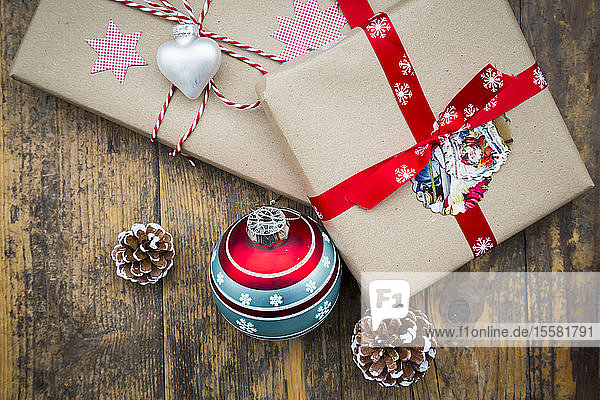 Eingepackte Weihnachtsgeschenke Weihnachtskugeln und Tannenzapfen auf dunklem Holz