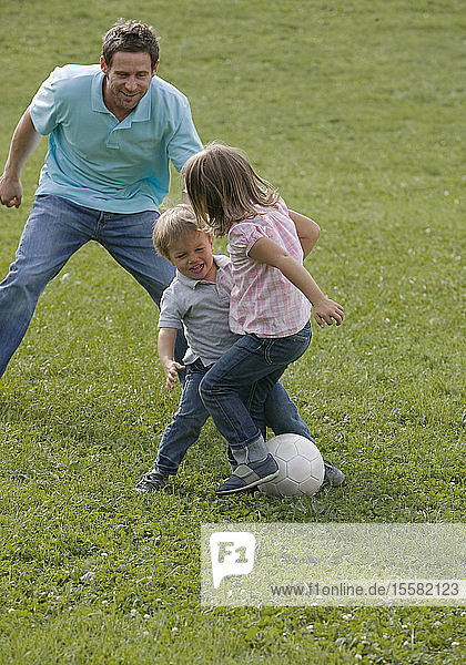 Vater spielt mit Kindern Fussball