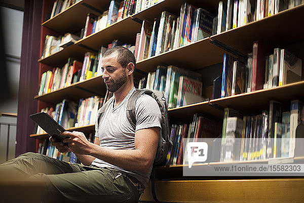 Student verwendet digitales Tablett in einer Bibliothek