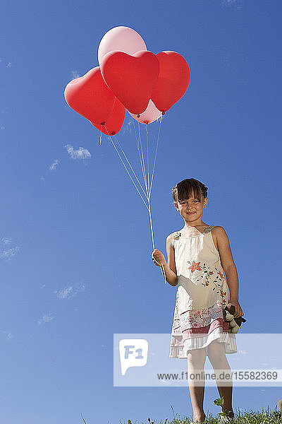 Mädchen (7-9) hält ein Bündel Ballons