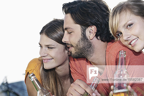 Deutschland  Köln  Junger Mann und Frau liegen mit Bierflaschen im Gras und lächeln