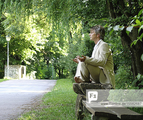 Mann auf Parkbank sitzend  meditierend