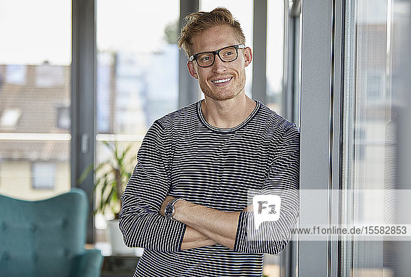 Portrait of smiling young man leaning against window