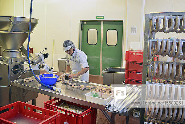 Frau arbeitet bei der Wurstproduktion in einer Metzgerei