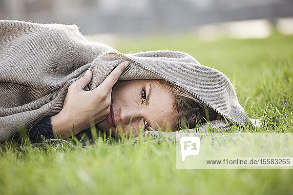 Germany  Cologne  Young woman lying in grass  portrait