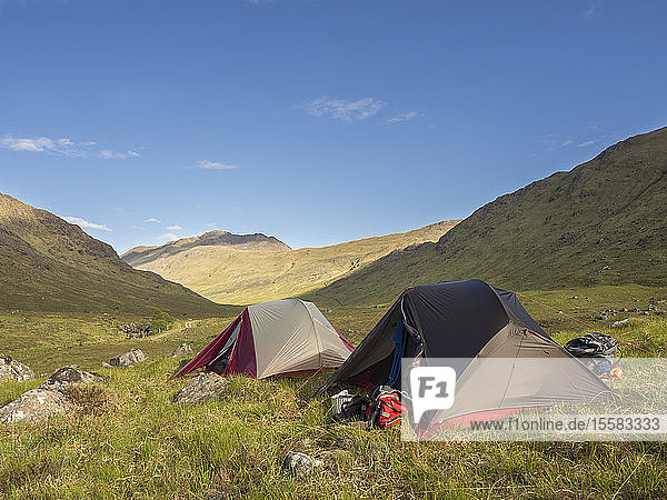 Zelte auf Grasland vor blauem Himmel bei sonnigem Wetter  Schottland  Großbritannien