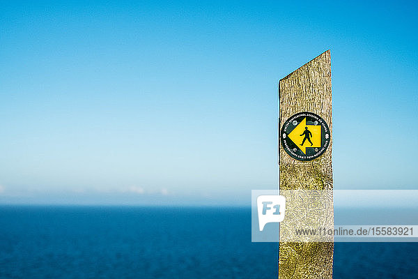 Steinwegweiser auf dem Pembrokeshire Coast Path National Trail  mit dem Ozean im Hintergrund.
