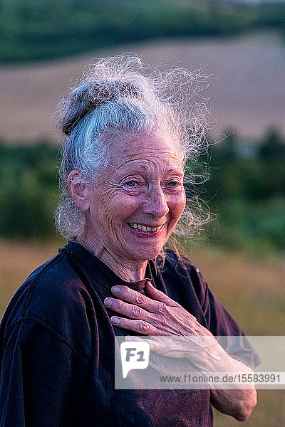 Ältere Frau  die an einem Yogakurs an einem Berghang teilnimmt.