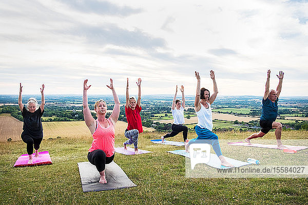 Gruppe von Frauen und Männern  die an einer Yogastunde an einem Berghang teilnahmen.