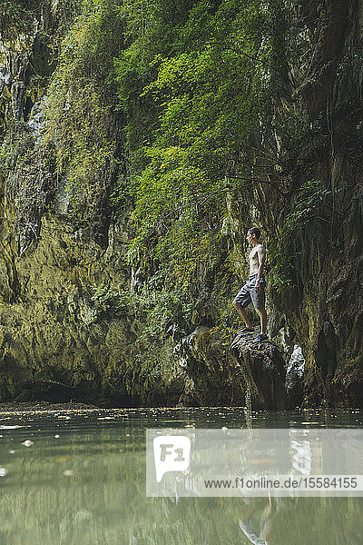 Shirtless man standing on rock in lake by cliffs in Krabi  Thailand