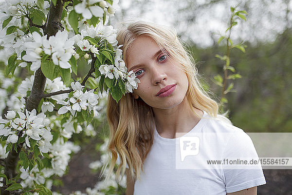 Blondhaarige junge Frau zwischen weißen Blüten