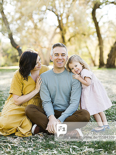 Mid adult couple sitting with their daughter in park