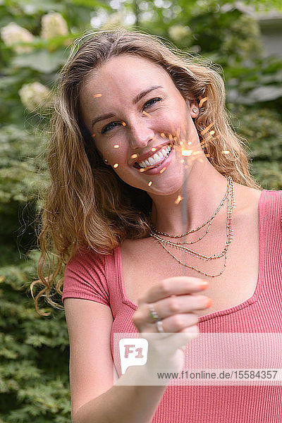 Smiling young woman holding sparkler