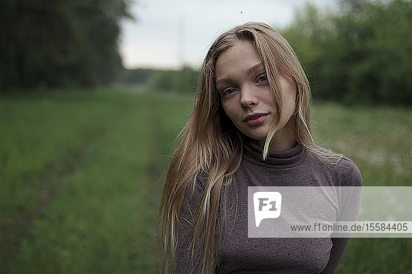 Porträt einer jungen Frau mit blondem Haar auf einem Feld