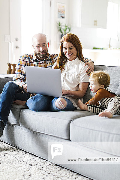 Family using laptop on sofa