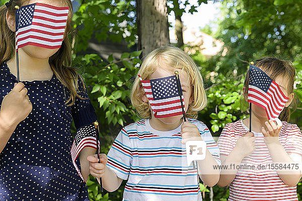 Children holding American flags over their faces
