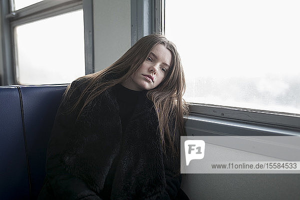 Junge Frau mit schwarzem Pelzmantel im Zug