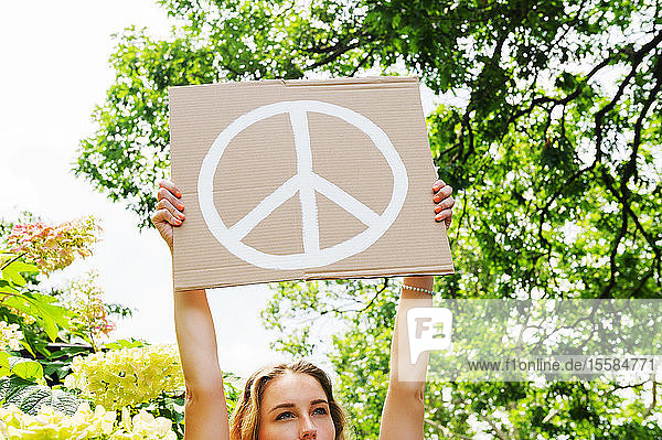Young woman holding aloft peace symbol