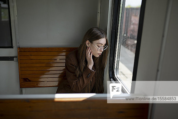 Junge Frau mit Brille am Fenster im Zug