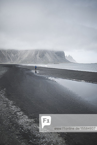 Mann spaziert am schwarzen Sandstrand in KirkjubÂµjarklaustur  Island