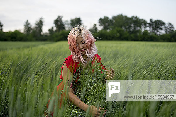 Frau mit rosa Haaren und rotem Kleid in einem Weizenfeld