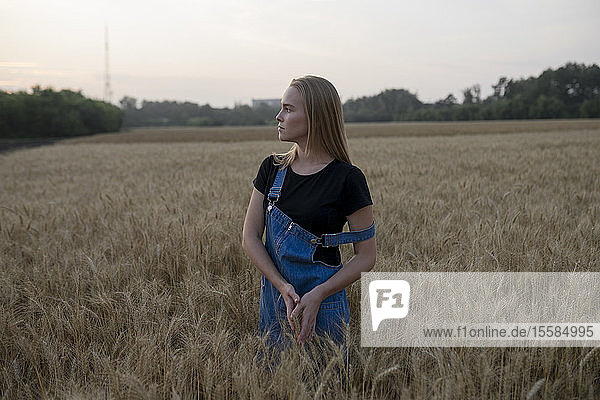 Junge Frau in Latzhose in einem Weizenfeld