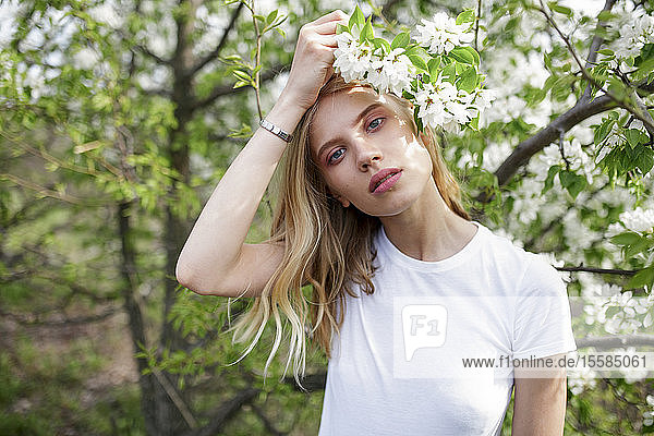 Blondhaarige junge Frau zwischen weißen Blüten