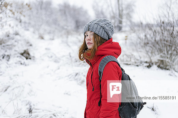 Teenage girl wearing red coat and grey hat in snow