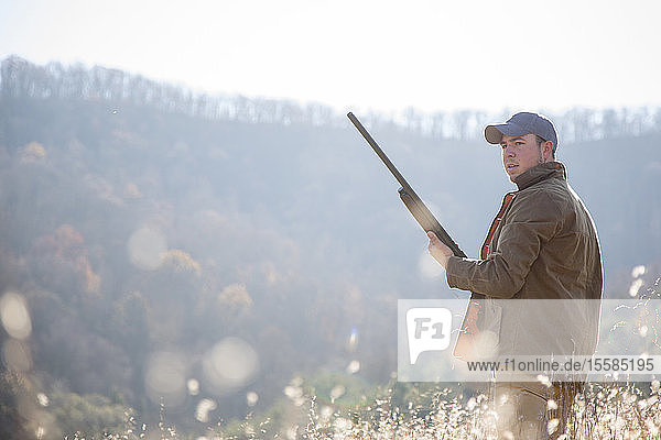 Young man holding rifle in field