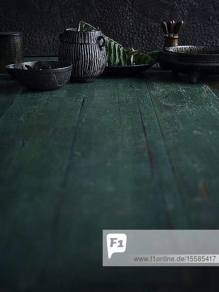 Rustic low key still life with bowls and jug on green wooden table