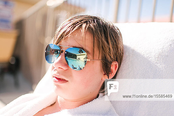 Cooler Teenager-Junge mit spiegelbildlicher Sonnenbrille auf einer Sonnenliege am Hotelpool  Kopf und Schultern  Las Vegas  Nevada  USA