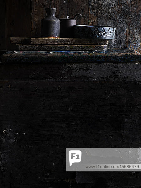 Rustic low key still life with ceramic bowl jar and pot on cutting boards surface level view