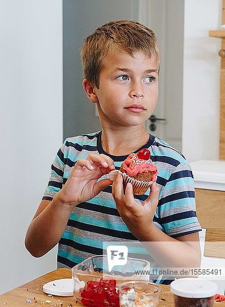 Boy holding cupcake at home