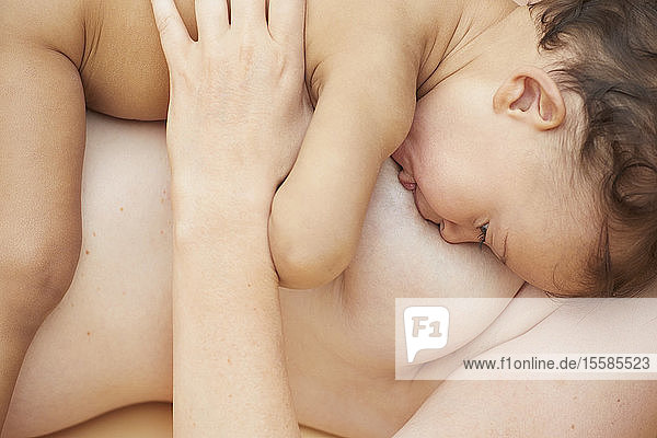 Nacktes Baby beim Saugen an der nackten Mutterbrust