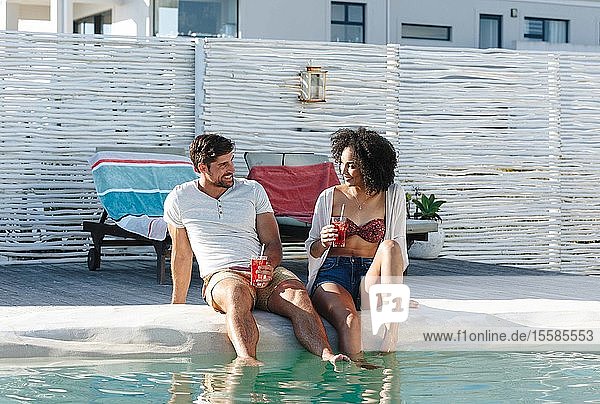 Couple enjoying iced drink by swimming pool